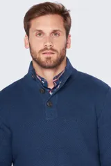 Buzo de tejido grueso color azul con botones personalizados en el cuello, estructura y detalle de cuero.