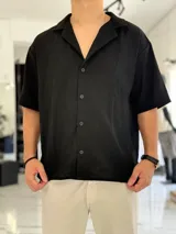 Camisa de lino color negro, de manga corta, con cuello solapa y cierre frontal con botones.