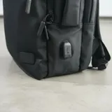Mochila de viaje color negro con múltiples compartimentos, bolsillos frontales con cierre, puerto USB integrado y diseño resistente al agua.