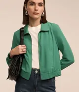 Campera bomber femenina color beige claro, confeccionada en tejido Airflow texturado. Presenta cuello solapa, cierre frontal de cremallera y puños y bajo elásticos.