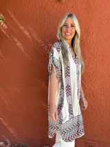 Camisa de seda con fondo crudo y estampado floral multicolor. Presenta cuello camisero, cierre frontal con botones y mangas cortas con diseño holgado.