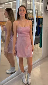 Vestido corto de lurex brillante color rosado, con escote recto, tirantes finos regulables y falda con vuelo.