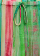Pantalon de corte recto y tiro medio, confeccionado en tejido fluido semitransparente con estampado de rayas verticales en tonos verdes, rojos y amarillos. Presenta cintura elástica con cierre de lazo ajustable.