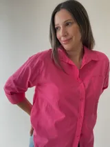 Camisa celeste de corte holgado, con cuello clásico, cierre frontal con botones, bolsillo en el pecho y mangas largas con puños abotonados.