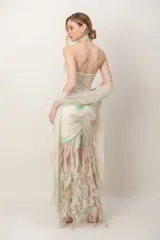Vestido largo de gasa con escote halter, volado central y falda con flecos, acompañado de foulard. Diseño estampado en tonos claros con detalles sutiles.