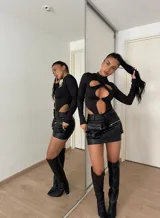 Body negro de lycra con cuello alto y mangas largas. Presenta aberturas en el pecho y abdomen unidas por un aro metálico.