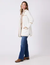 Chaqueta de silueta estructurada y calce recto, confeccionada en tejido jacquard con relieve floral. Presenta cuello con solapas, frente abierto y dos bolsillos de parche frontales. Se destaca por sus vivos a contratono que bordean las solapas, los bolsillos y las costuras horizontales, además de contar con tajos laterales en el ruedo.