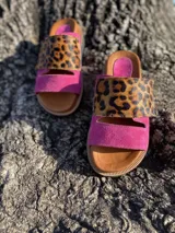 Sandalias bajas con base color suela, tira ancha de cuero fucsia y tira superior de animal print.