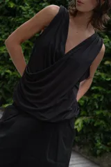 Blusa negra sin mangas con escote en V cruzado y drapeado en la parte delantera.