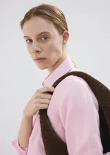 Camisa de lino color rosado, con diseño recto, cuello camisero, manga larga con puños abotonados y cierre frontal de botones.