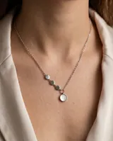 Collar de plata con cadena de eslabones finos y diseño asimétrico que incluye tres pequeños discos metálicos y un dije circular principal con incrustación de nácar.