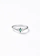 Anillo de plata 925 con diseño delicado, presenta una piedra central verde en corte marquesa flanqueada por pequeñas zirconias transparentes.