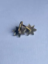 Aros tipo argolla dorada con dije colgante en forma de estrella de acrílico color rosa.