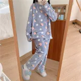 Conjunto de pijama de dos piezas confeccionado en plush suave, compuesto por una remera de manga larga y pantalón largo. Presenta un diseño estampado de duraznos sobre fondo color crema.