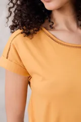 Remera negra de algodón peinado, ajustada al cuerpo, con cuello redondo y detalles de vainillas caladas en el escote y los hombros. Las mangas son cortas y están dobladas hacia afuera.