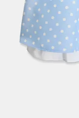 Vestido corto de tirantes finos ajustables, color celeste con estampado de lunares blancos. Presenta un forro blanco asimétrico que asoma en el ruedo.
