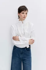 Blusa celeste de manga larga con puños fruncidos y elásticos, escote en V con cuello alto con volados y delicados bordados florales en el pecho.