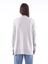 Saco gris melange de tejido de punto, sin cierre, con cuello en V y bolsillos frontales.