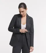 Blazer alargado color gris oscuro, con cuello solapa, bolsillos incorporados y cierre frontal con dos botones.