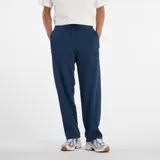 Pantalón deportivo New Balance modelo Track Pant, color azul marino, de corte ancho y holgado, con cordón ajustable en la cintura y un pequeño parche con logo en el muslo.