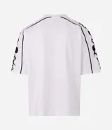 Remera de corte boxy y silueta amplia, color blanco con cuello redondo. Presenta estampa frontal con texto y gráficos tribales en las mangas.