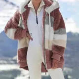 Campera peluda de mujer marca United Uy, con capucha y cierre frontal de cremallera. Presenta diseño de rayas horizontales en bloques de colores blanco, gris, beige y negro, con textura de piel sintética y puños elásticos.