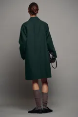 Trench midi ZW Collection verde oscuro con cuello solapa, manga larga, bolsillos laterales en costura y cierre frontal con botones. Cuenta con forro interior a contraste y detalle de solapa corta en el pecho.