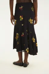 Falda midi de corte evasé con diseño cruzado y volado asimétrico. Confeccionada en tejido negro de caída fluida con estampado floral y motivos de leopardos y vegetación.