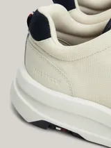 Zapatillas Tommy Hilfiger de cuero color blanco con detalles en azul marino. Presentan cordones azul marino, suela gruesa blanca y logo de la marca en el lateral.