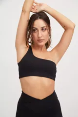 Top deportivo negro asimétrico con un solo tirante ancho, confeccionado en tejido Compress con protección UV50+ y fibras biodegradables.