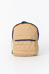 Mochila de color beige con diseño capitoneado hexagonal. Presenta un compartimento principal y un bolsillo frontal con cierres en contraste de colores azul y naranja, además de tiradores de cordón decorativos.