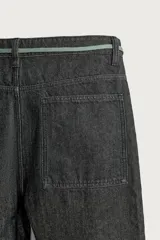 Jeans wide fit de denim negro, con costuras y detalles en color verde claro, bolsillos laterales y traseros, y cintura ajustable con cordón integrado.