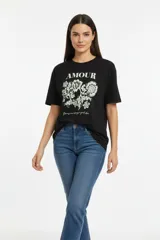 Remera de manga corta y cuello redondo, confeccionada en algodón. Presenta un estampado frontal con la palabra 'AMOUR' y un diseño floral detallado en tonos claros sobre fondo negro.
