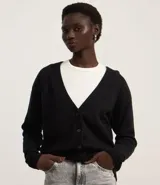 Cardigan corto de punto color marrón, con cuello en V, manga larga y cierre frontal con botones. Presenta puños y bajo acanalados.