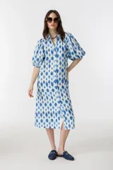 Vestido midi de lino con estampado floral azul y blanco, cuello clásico, mangas abullonadas hasta el codo y cierre frontal con botones de nácar.