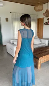 Vestido largo de microtul bordó, sin mangas, con escote alto tipo buche y diseño transparente con forro corto interno que genera un efecto translúcido en la falda.