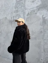 Campera de piel sintética negra, con diseño de pelo largo, cuello alto y cierre frontal.