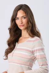 Remera de manga larga con cuello redondo y cierre frontal parcial con botones. Presenta un diseño de rayas horizontales en tonos pastel en la parte superior y un detalle de abertura lateral en el ruedo.