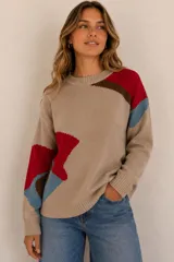 Buzo de punto color beige con diseño geométrico y abstracto en tonos rojo, azul y marrón, de corte holgado, cuello redondo y mangas largas.