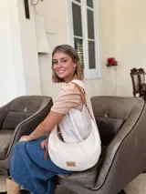 Cartera tipo hobo de cuero color crudo con correa de cuero marrón.