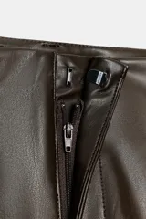 Pantalón jogger de tiro medio confeccionado en tejido efecto piel. Presenta pliegues en el delantero, bolsillos laterales, falsos bolsillos de vivo en la parte posterior y bajo acabado en elástico. Cierre frontal con cremallera, botón interior y gancho metálico.