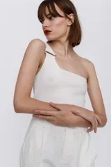 Top tejido de un hombro color blanco, con detalle de hebilla de metal en el tirante.