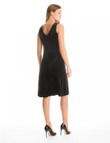 Vestido midi sin mangas confeccionado en terciopelo negro. Presenta escote redondo cerrado en el frente y un profundo escote en V en la espalda. Su diseño sigue la línea del cuerpo con pinzas de entalle laterales y una falda que se abre ligeramente hacia el ruedo.