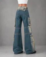 Pantalón cargo de jean azul con efecto gastado, tiro ajustable que permite usarlo alto o bajo mediante un cierre lateral, bolsillos cargo grandes en los laterales y diseño de pierna ancha.