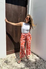 Pantalón amplio color naranja con estampado abstracto en blanco, cintura elastizada y bolsillos laterales.