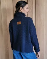 Sweater de lana color crudo con cuello alto y diseño trenzado.