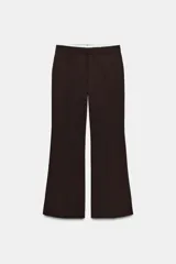 Pantalón de tiro bajo color marrón, con bolsillos frontales, falsos bolsillos traseros de vivo y cierre delantero con cremallera y gancho metálico.
