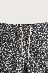 Short de baño largo con estampado geométrico en tonos oscuros sobre fondo claro, cintura elástica ajustable con cordón y bolsillos laterales.