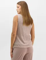 Conjunto de tres piezas compuesto por una musculosa recta, un cardigan liviano de frente abierto con mangas 3/4 y un pantalón de seda fría. La musculosa y el cardigan están confeccionados en tejido plisado con hilos metalizados tornasolados. Incluye collar removible y forro interno a tono.