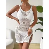 Vestido corto de playa color blanco, confeccionado en tejido calado con diseño geométrico y floral. Es de corte recto al cuerpo, sin mangas, con escote redondo y un tajo lateral.